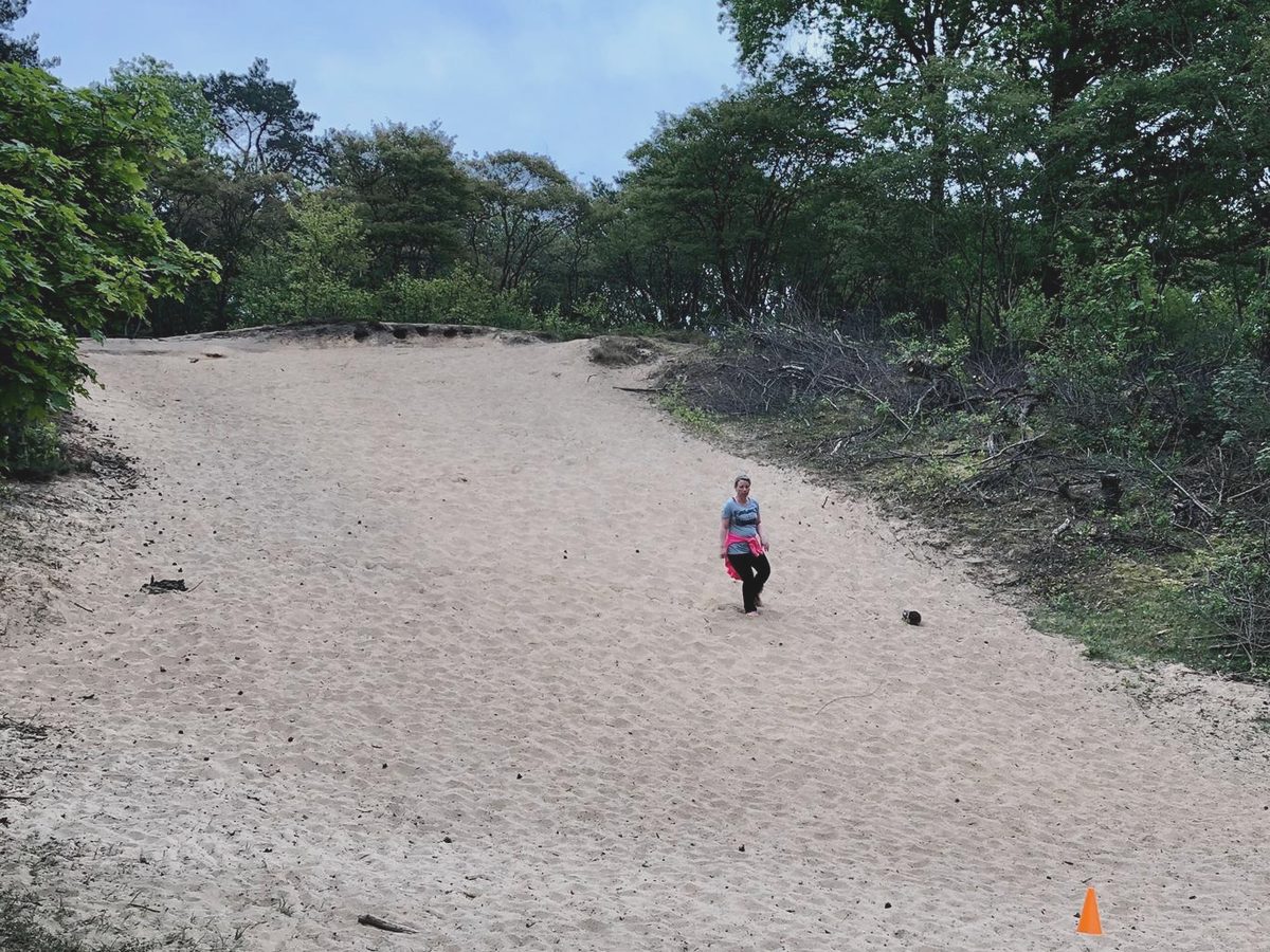 Een persoon traint klein in beeld op een leeg strand